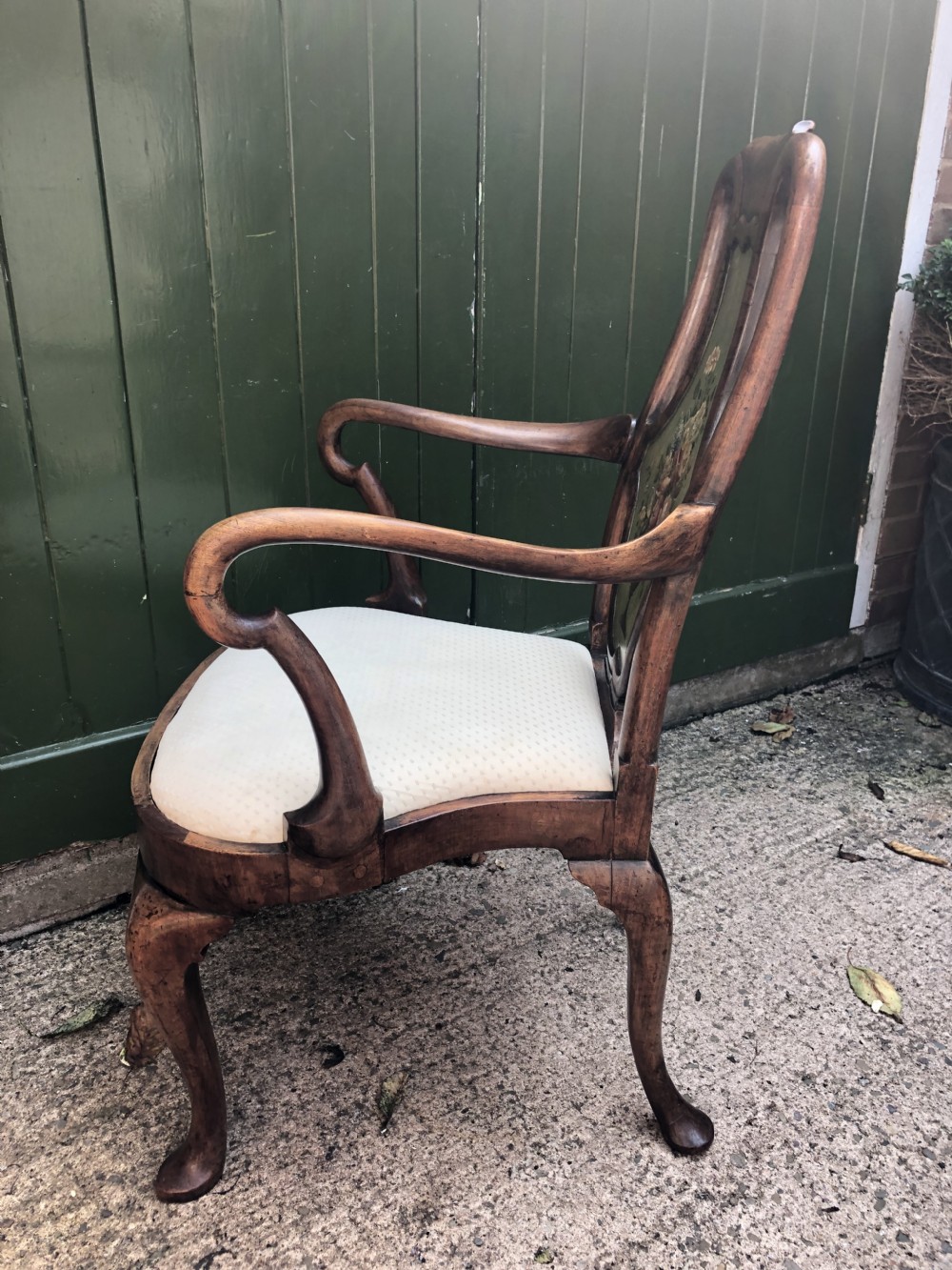 Early 20th-century Queen Anne revival walnut armchair featuring a painted floral splat back, carved armrests, cabriole legs, and cream upholstery. View III