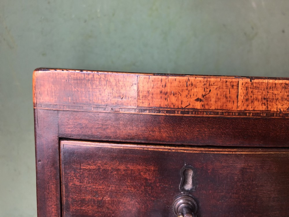 An early nineteenth-century miniature mahogany bow-front chest of drawers featuring brass ring handles and keyholes. View XII