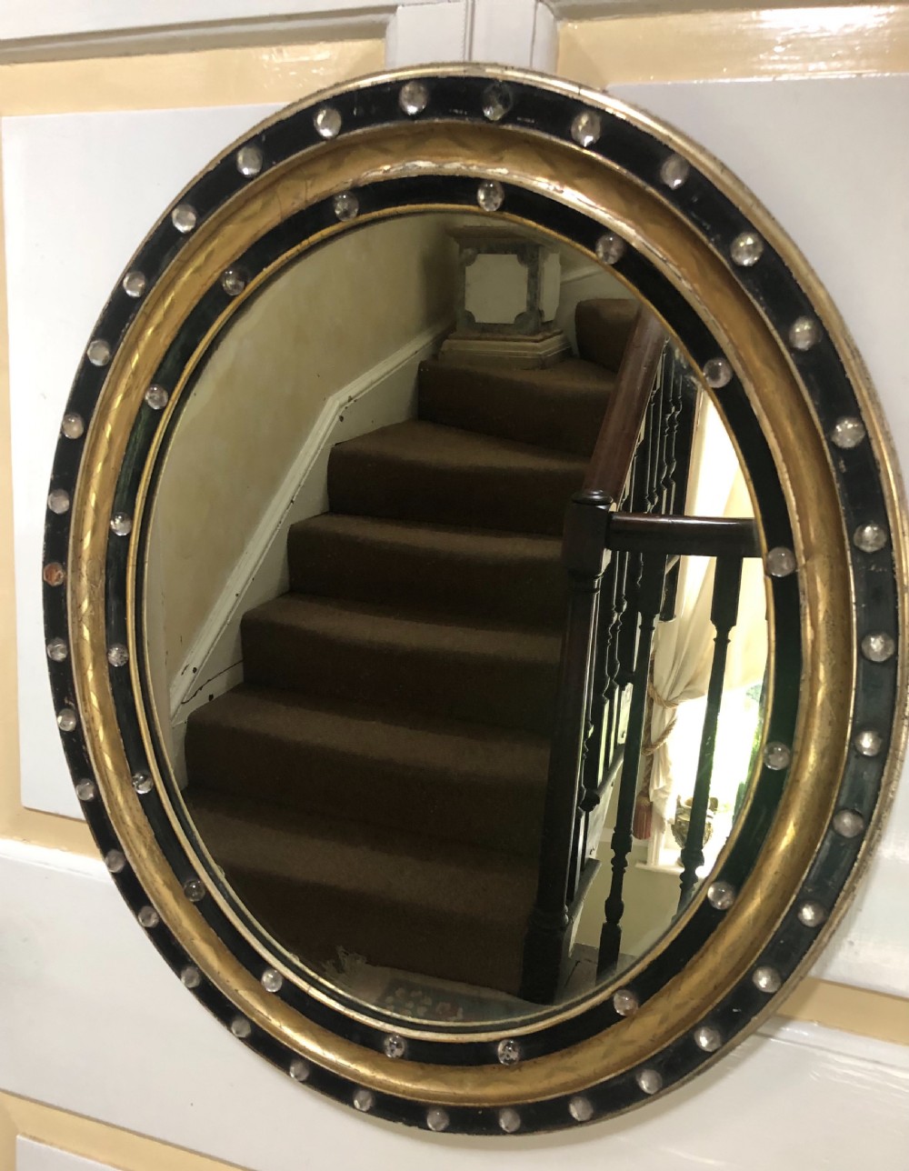 C19th Irish oval mirror with ebonised and gilded glass facet mounted frame with silvered outer edge .
