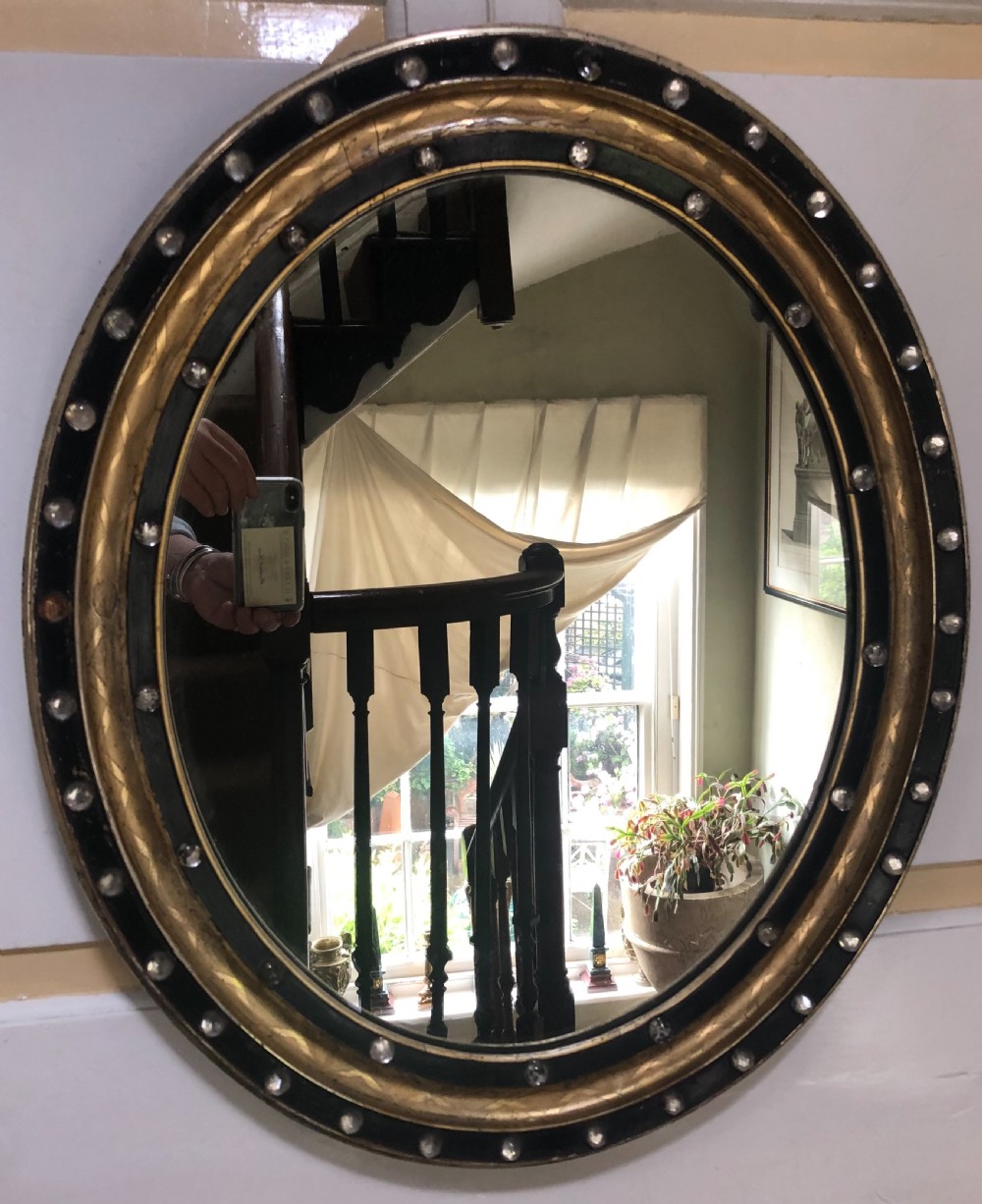 C19th Irish oval mirror with ebonised and gilded glass facet mounted frame with silvered outer edge . View III