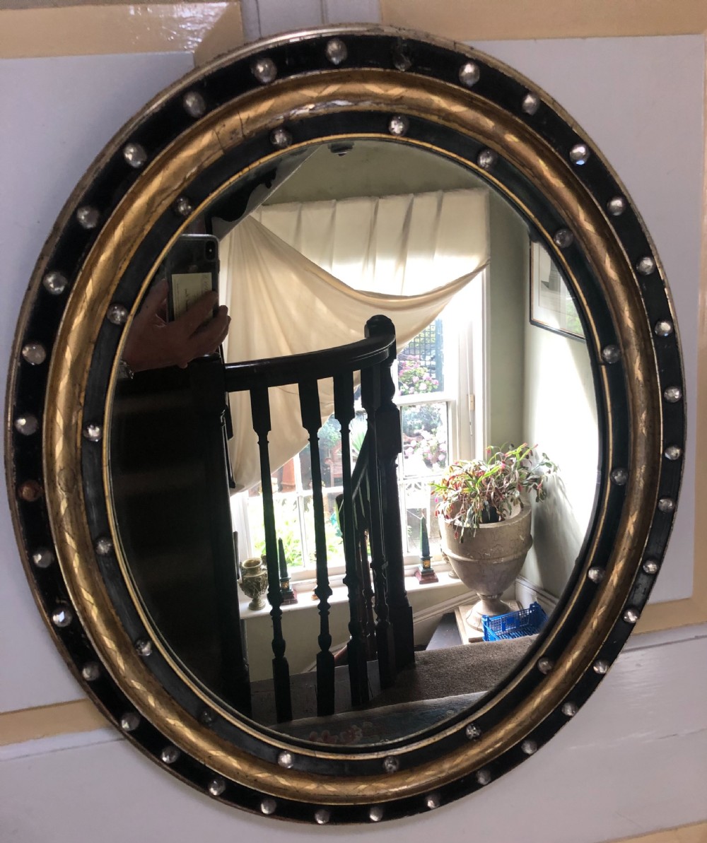 C19th Irish oval mirror with ebonised and gilded glass facet mounted frame with silvered outer edge . View IX