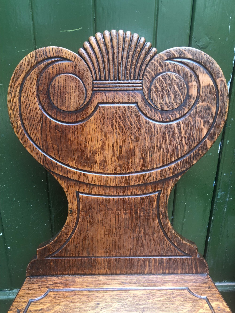 A pair of early nineteenth-century Regency oak hall chairs featuring carved scroll backs with shell motifs, solid timber seats, and reeded front legs. View VIII