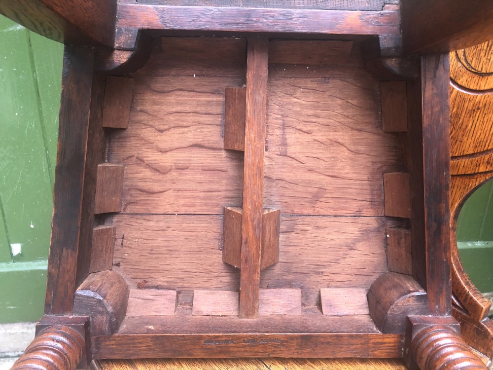 A pair of early nineteenth-century Regency oak hall chairs featuring carved scroll backs with shell motifs, solid timber seats, and reeded front legs. View XV