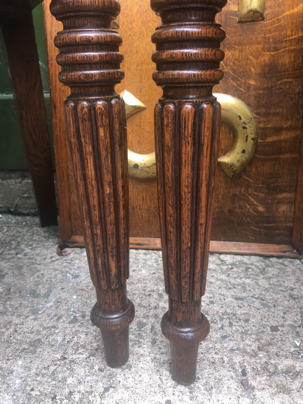 A pair of early nineteenth-century Regency oak hall chairs featuring carved scroll backs with shell motifs, solid timber seats, and reeded front legs. View XIX