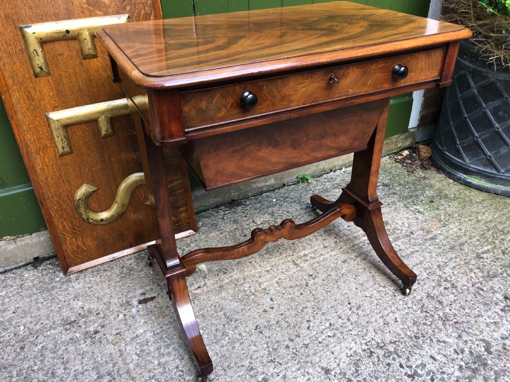 A George IV mahogany work table featuring a single drawer with turned knobs, a tapered lower well, carved trestle supports, and brass castors. View II