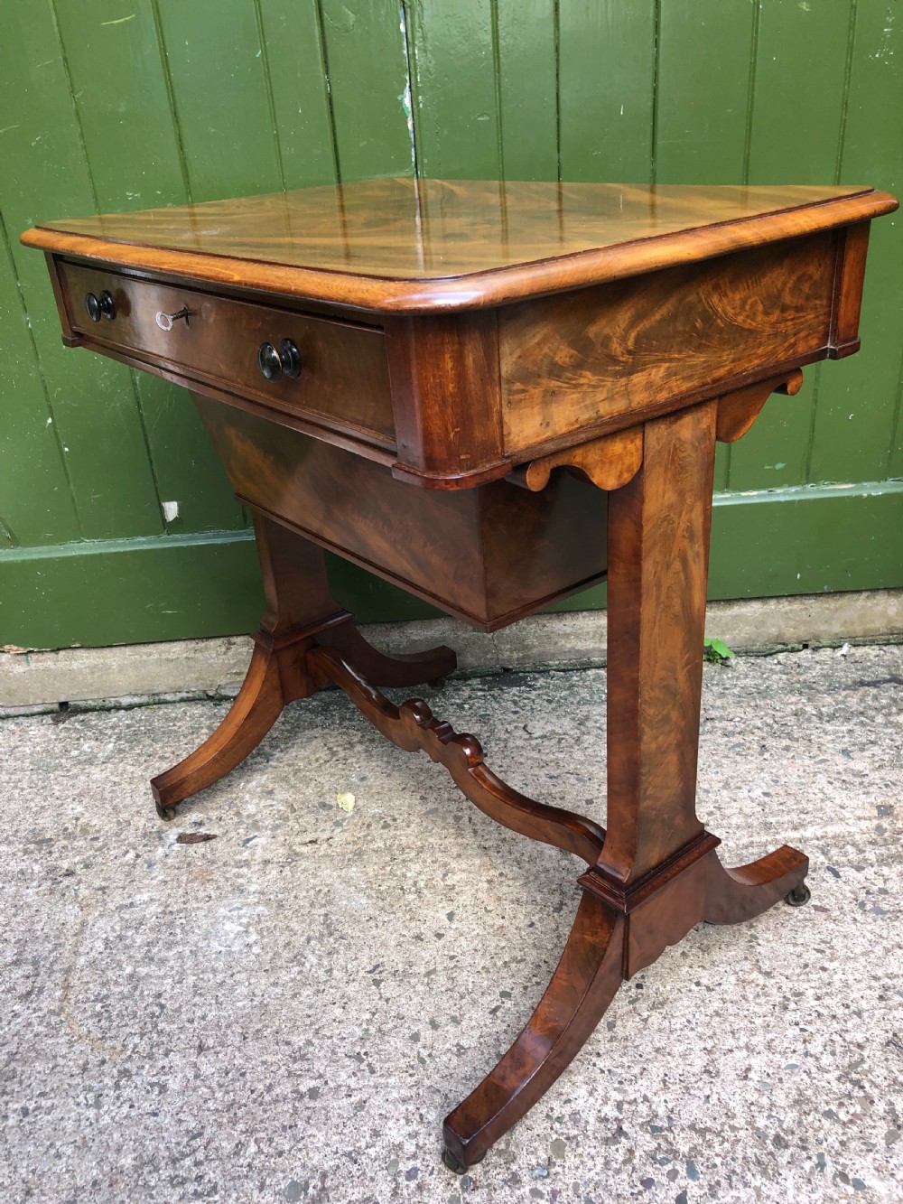A George IV mahogany work table featuring a single drawer with turned knobs, a tapered lower well, carved trestle supports, and brass castors. View VIII