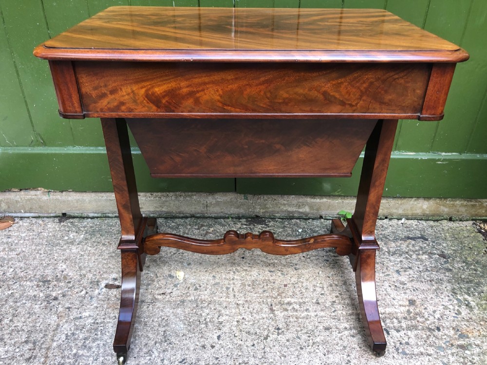 A George IV mahogany work table featuring a single drawer with turned knobs, a tapered lower well, carved trestle supports, and brass castors. View XI