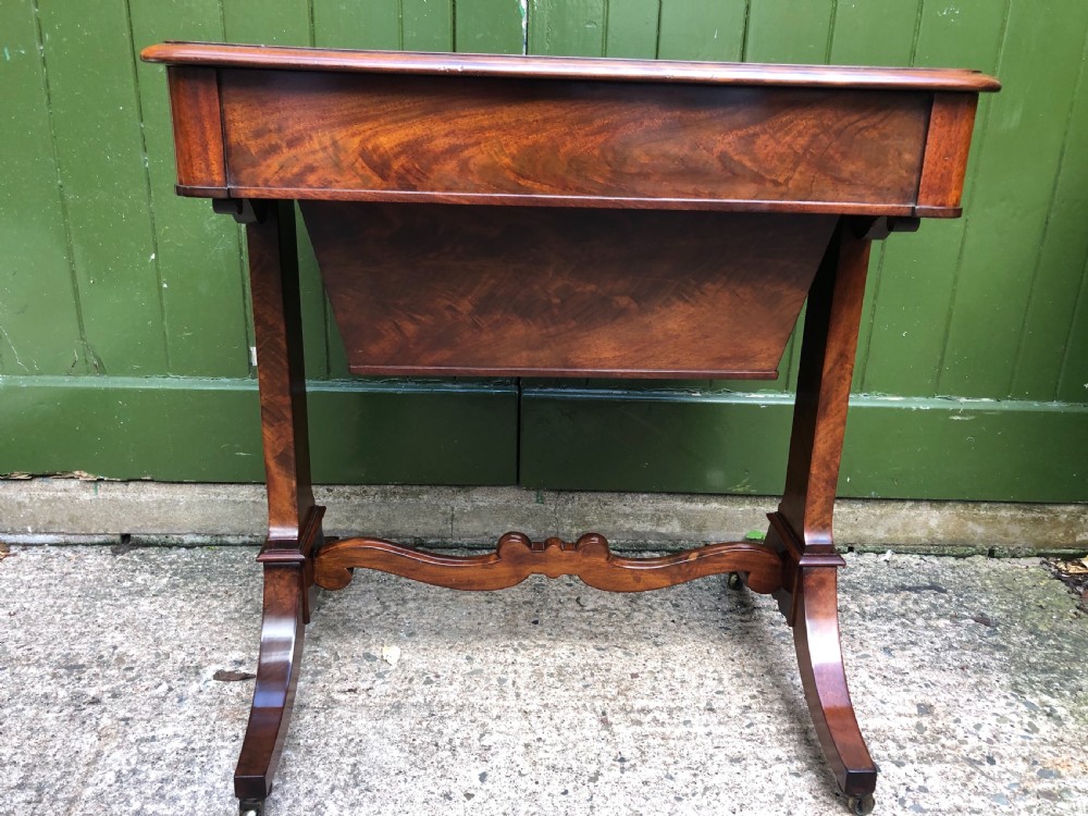 A George IV mahogany work table featuring a single drawer with turned knobs, a tapered lower well, carved trestle supports, and brass castors. View XII