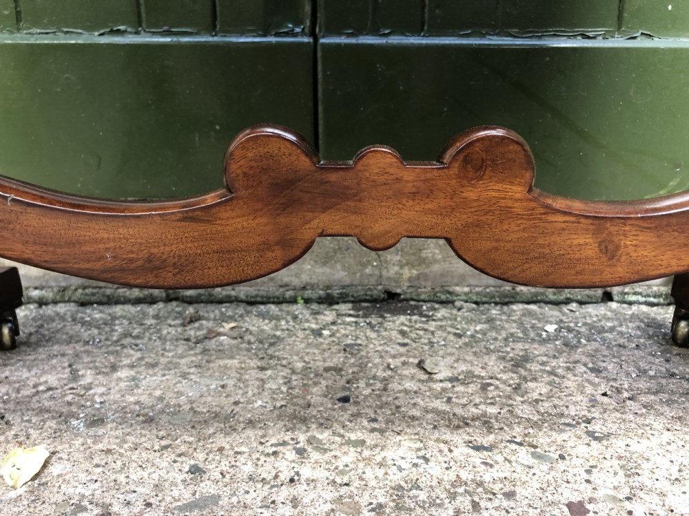 A George IV mahogany work table featuring a single drawer with turned knobs, a tapered lower well, carved trestle supports, and brass castors. View XIII