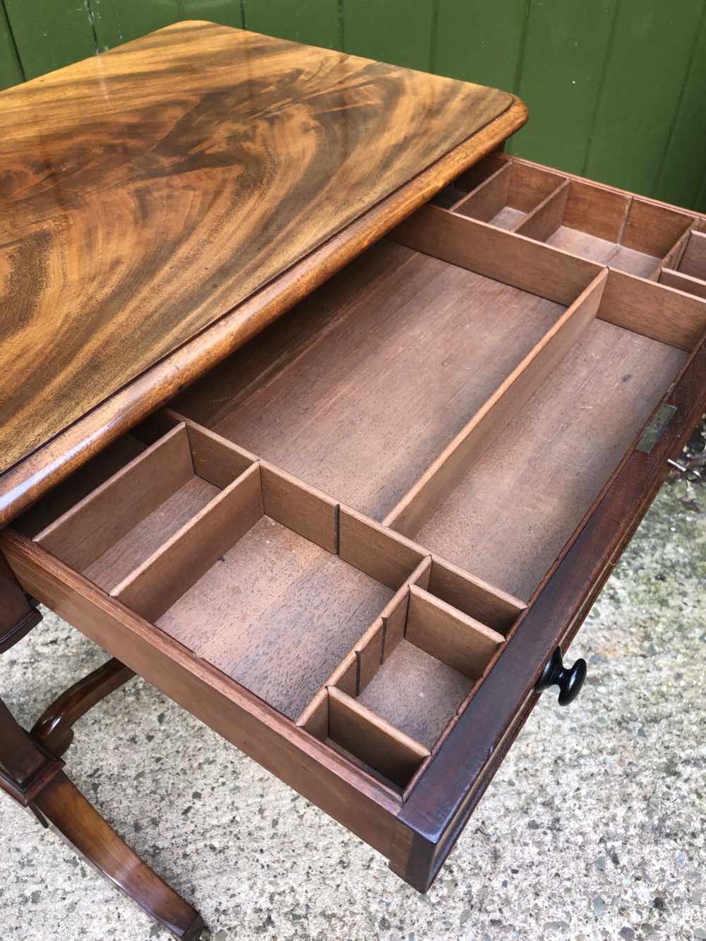 A George IV mahogany work table featuring a single drawer with turned knobs, a tapered lower well, carved trestle supports, and brass castors. View XV