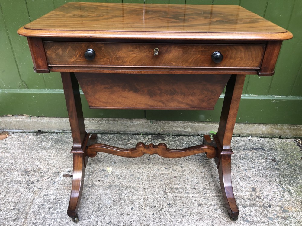A George IV mahogany work table featuring a single drawer with turned knobs, a tapered lower well, carved trestle supports, and brass castors. View XVII