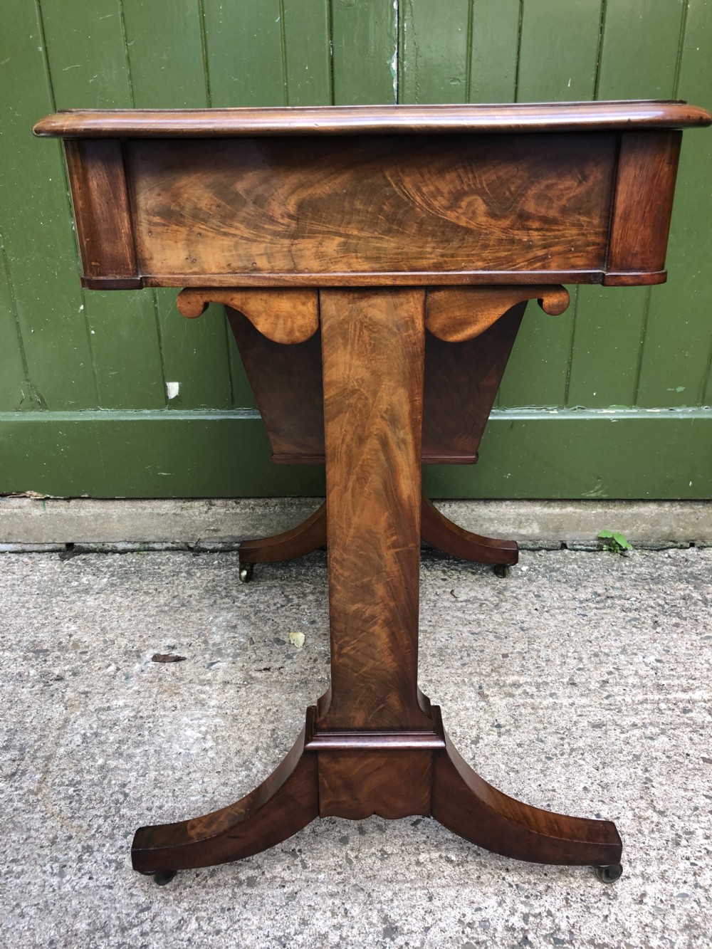 A George IV mahogany work table featuring a single drawer with turned knobs, a tapered lower well, carved trestle supports, and brass castors. View XIX