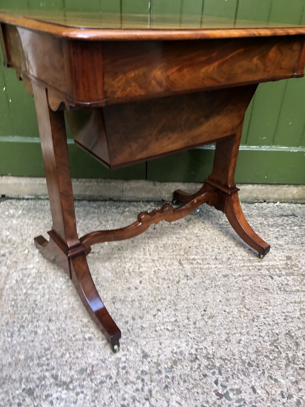 A George IV mahogany work table featuring a single drawer with turned knobs, a tapered lower well, carved trestle supports, and brass castors. View XXIII