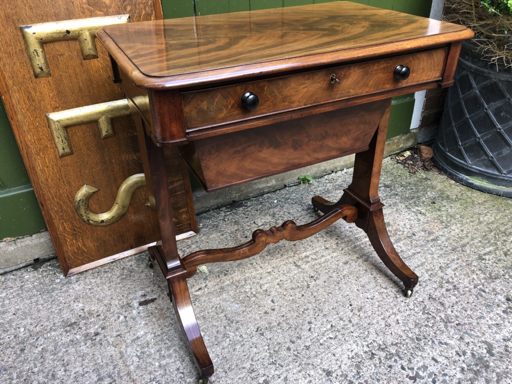 A George IV mahogany work table featuring a single drawer with turned knobs, a tapered lower well, carved trestle supports, and brass castors. View XXVI