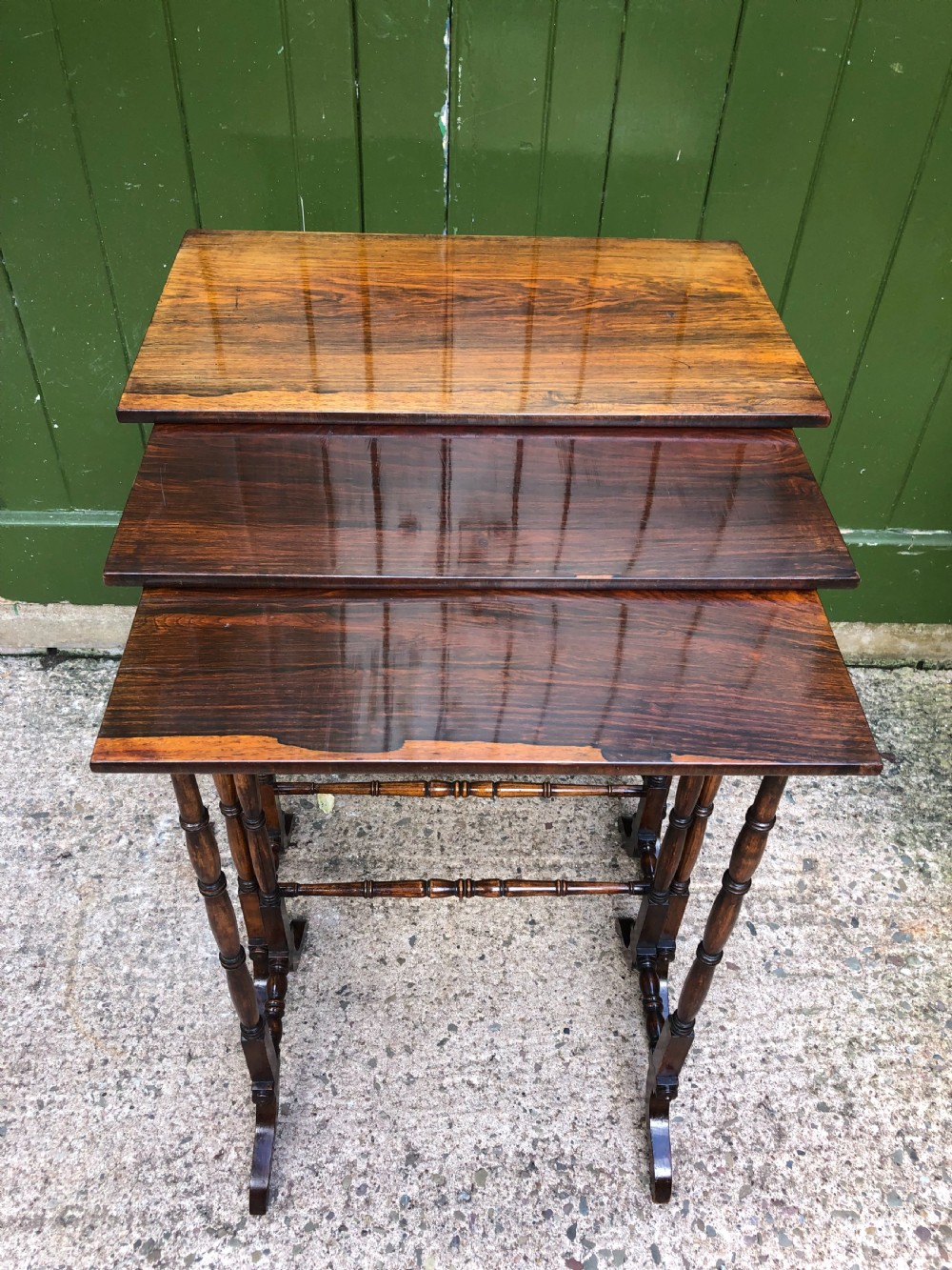 A set of three graduated Regency rosewood nesting tables featuring rectangular tops, slender turned spindle legs, and trestle bases. View II