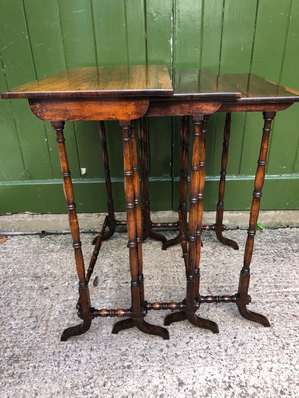A set of three graduated Regency rosewood nesting tables featuring rectangular tops, slender turned spindle legs, and trestle bases. View III