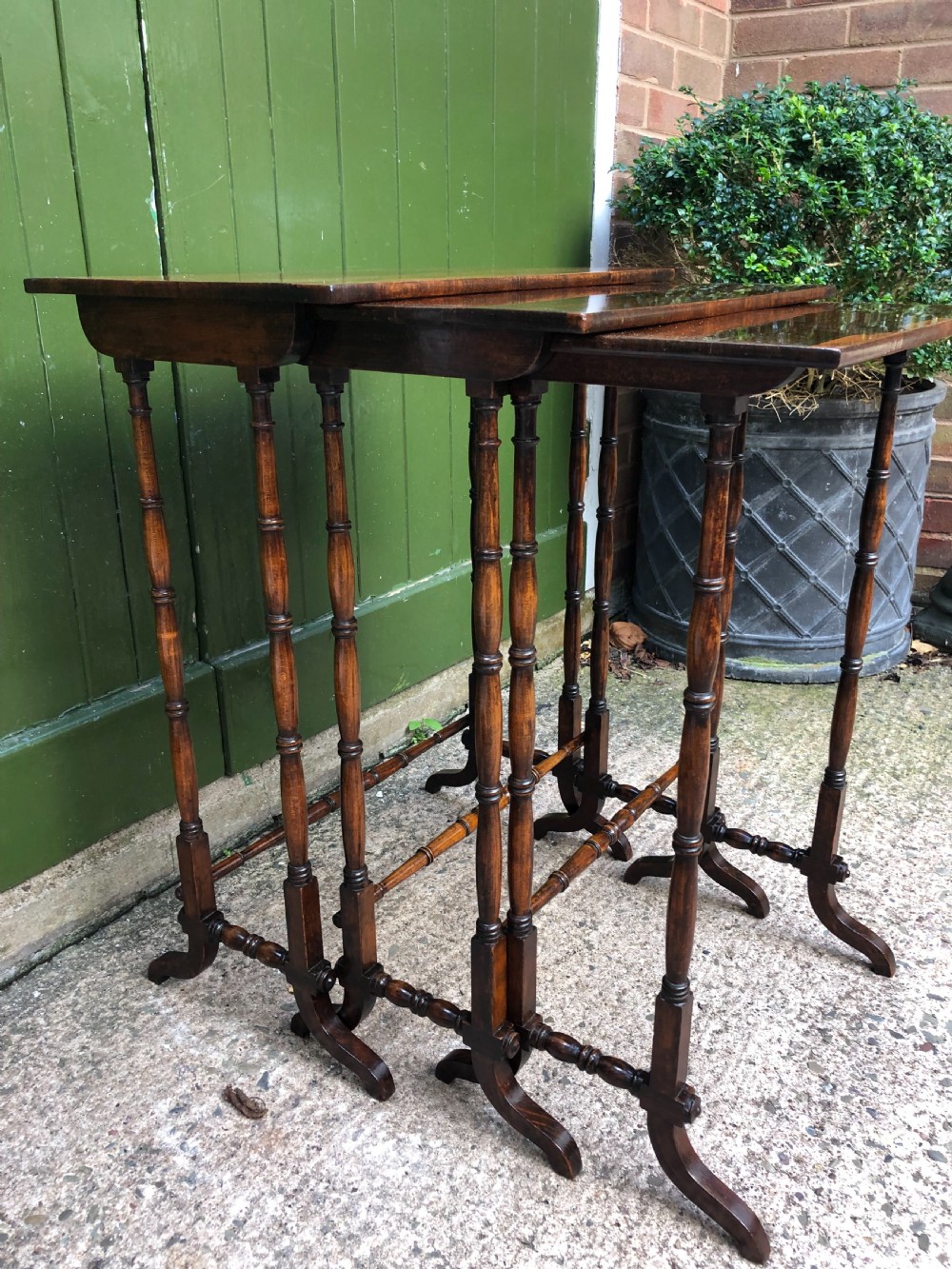 A set of three graduated Regency rosewood nesting tables featuring rectangular tops, slender turned spindle legs, and trestle bases. View V