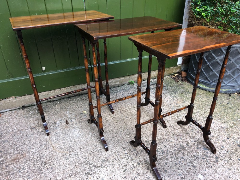 A set of three graduated Regency rosewood nesting tables featuring rectangular tops, slender turned spindle legs, and trestle bases. View VI