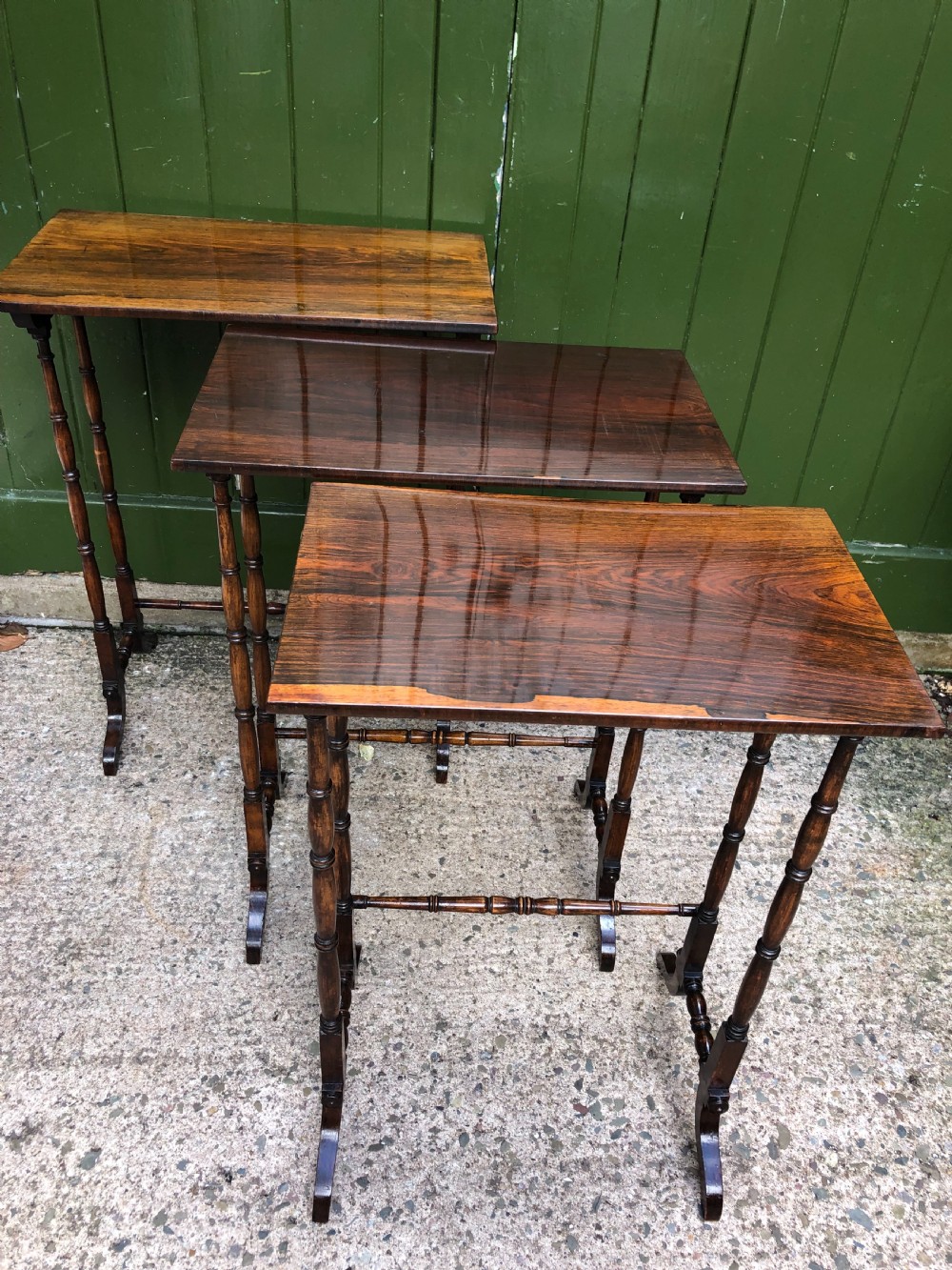 A set of three graduated Regency rosewood nesting tables featuring rectangular tops, slender turned spindle legs, and trestle bases. View VII