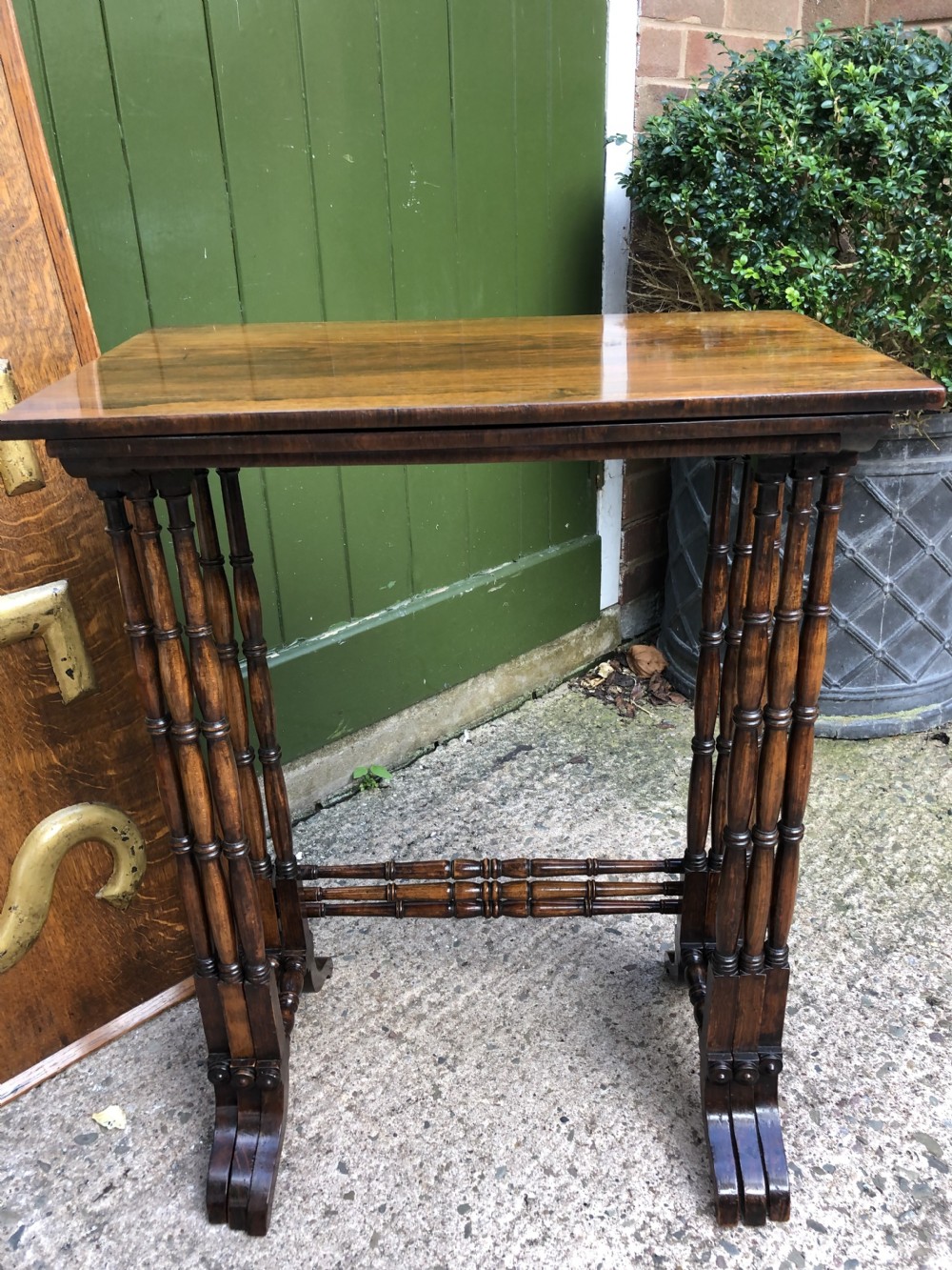 A set of three graduated Regency rosewood nesting tables featuring rectangular tops, slender turned spindle legs, and trestle bases. View XIX