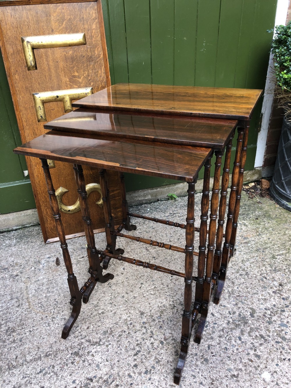 A set of three graduated Regency rosewood nesting tables featuring rectangular tops, slender turned spindle legs, and trestle bases. View XX