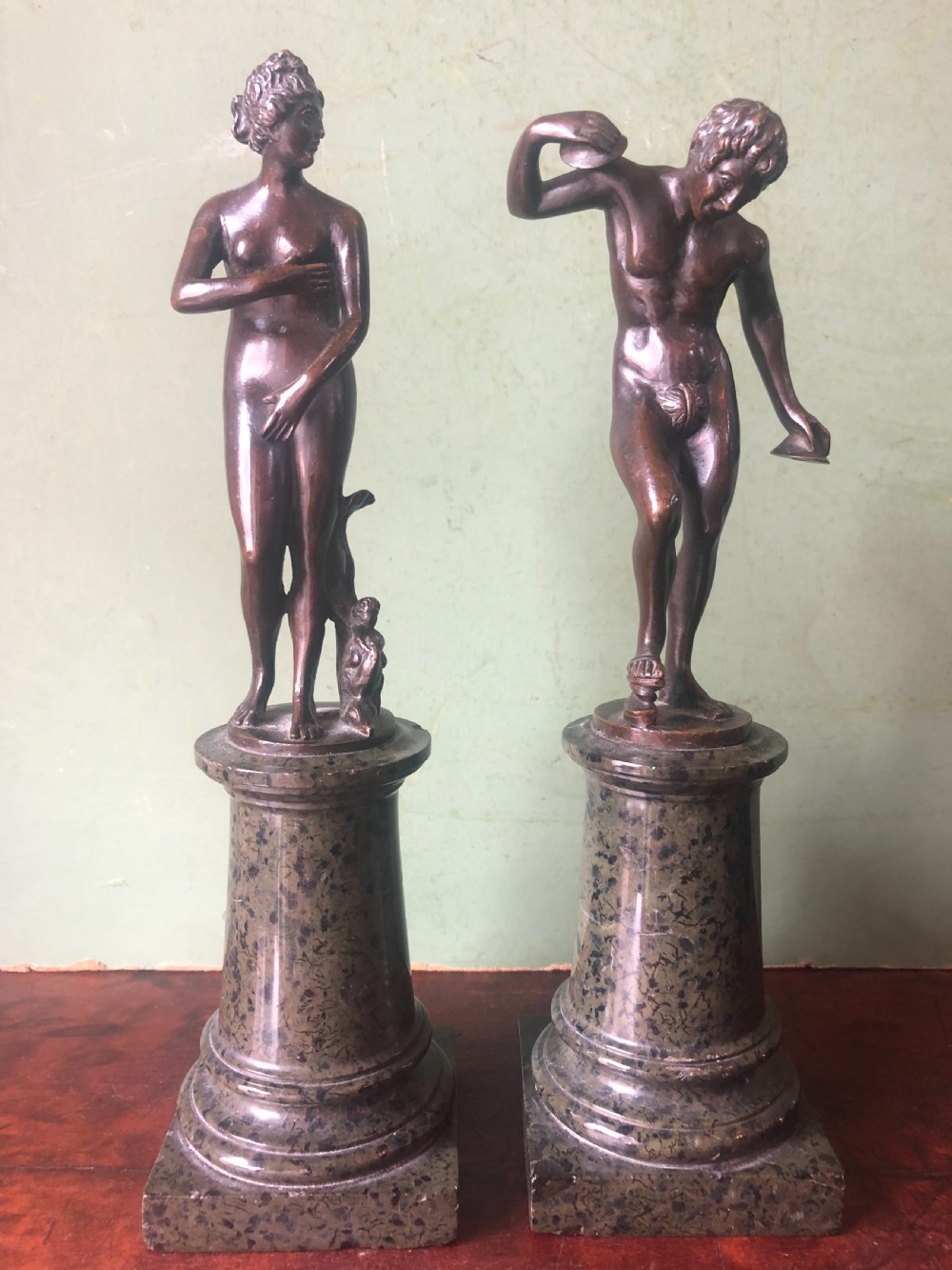 A pair of late nineteenth-century dark patinated bronze classical nude figures mounted on tall cylindrical dark marble column bases.