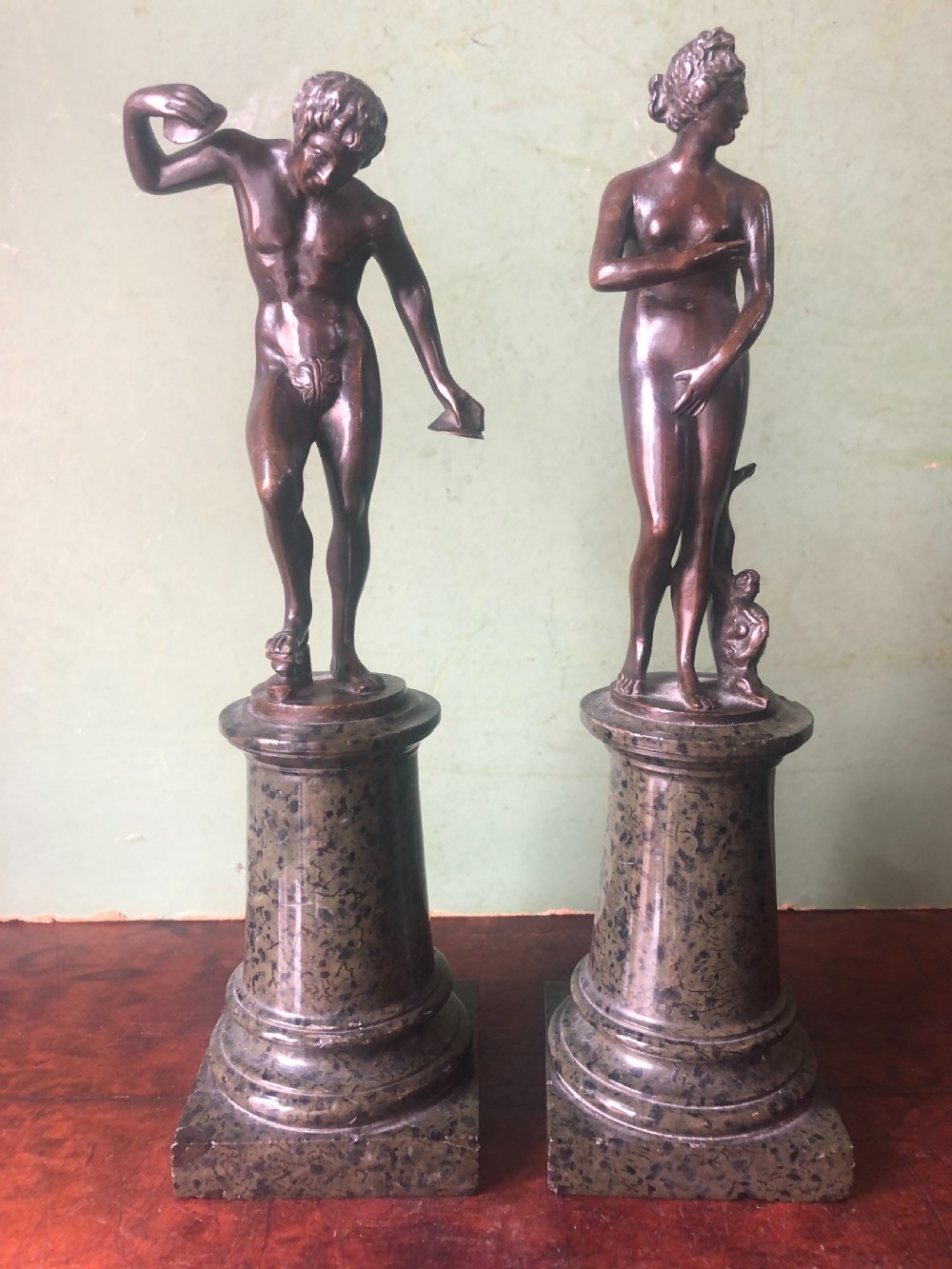A pair of late nineteenth-century dark patinated bronze classical nude figures mounted on tall cylindrical dark marble column bases. View II