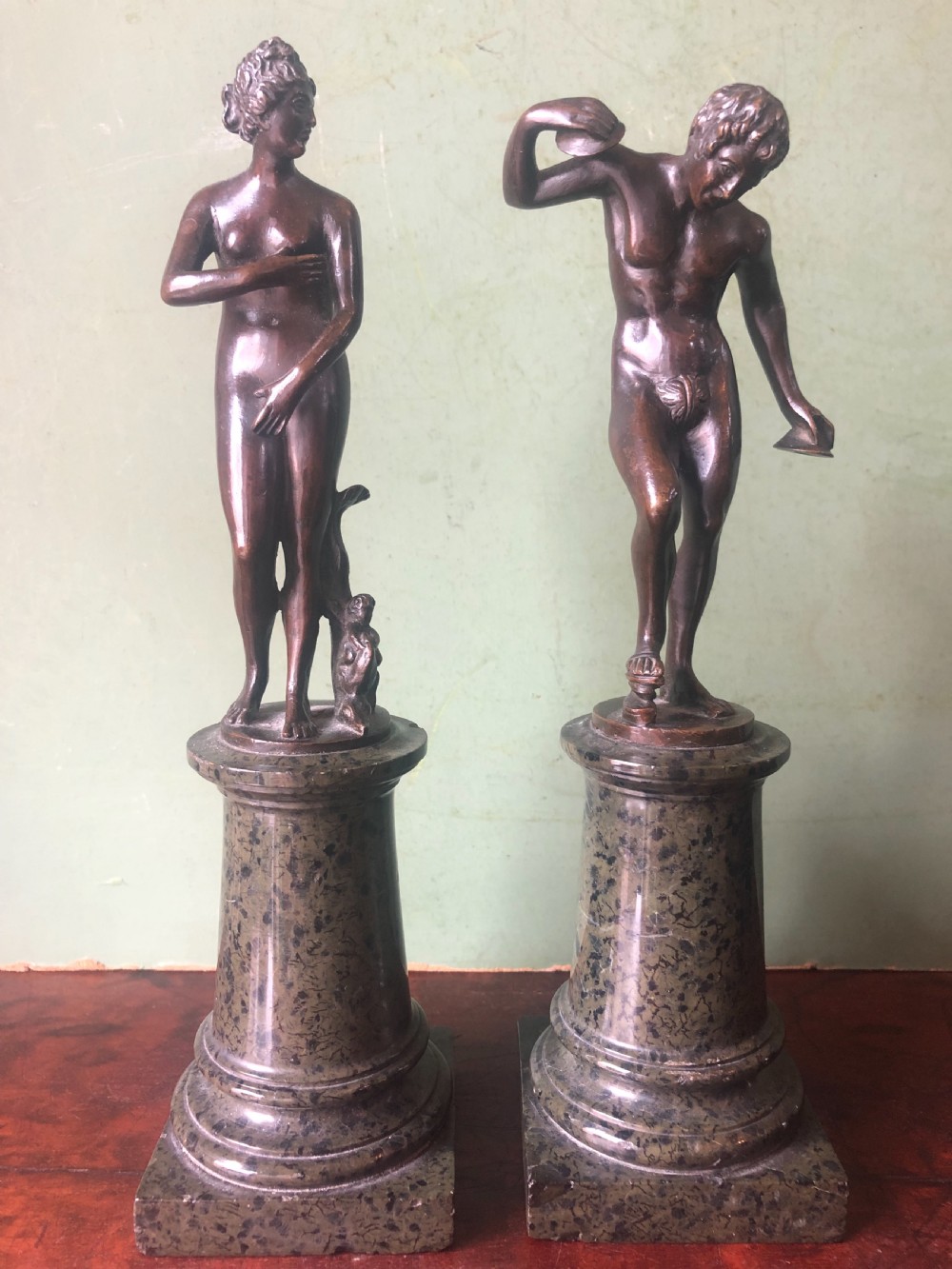 A pair of late nineteenth-century dark patinated bronze classical nude figures mounted on tall cylindrical dark marble column bases. View III