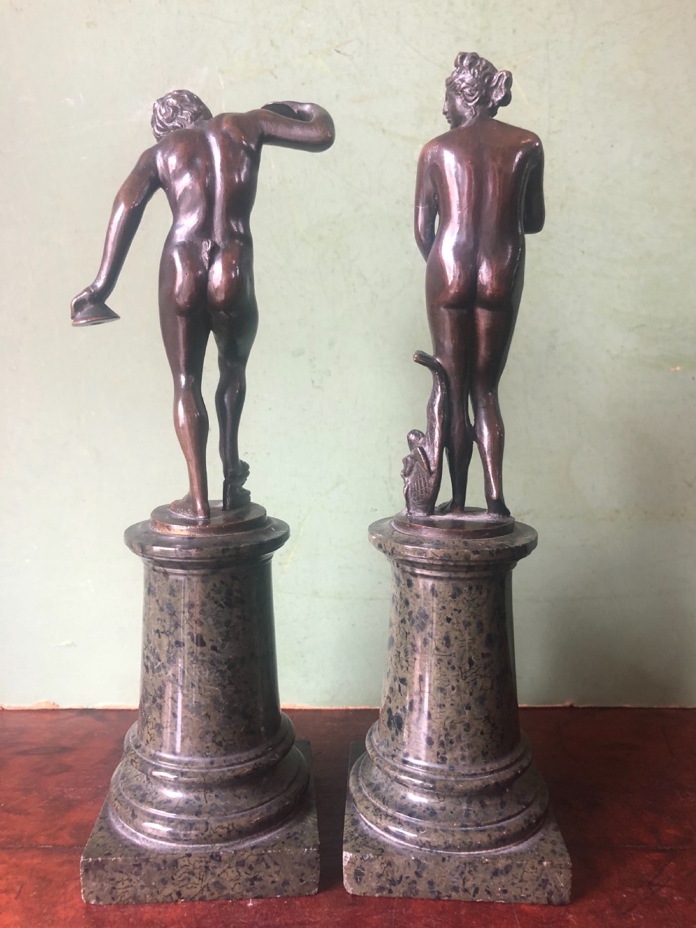 A pair of late nineteenth-century dark patinated bronze classical nude figures mounted on tall cylindrical dark marble column bases. View IX