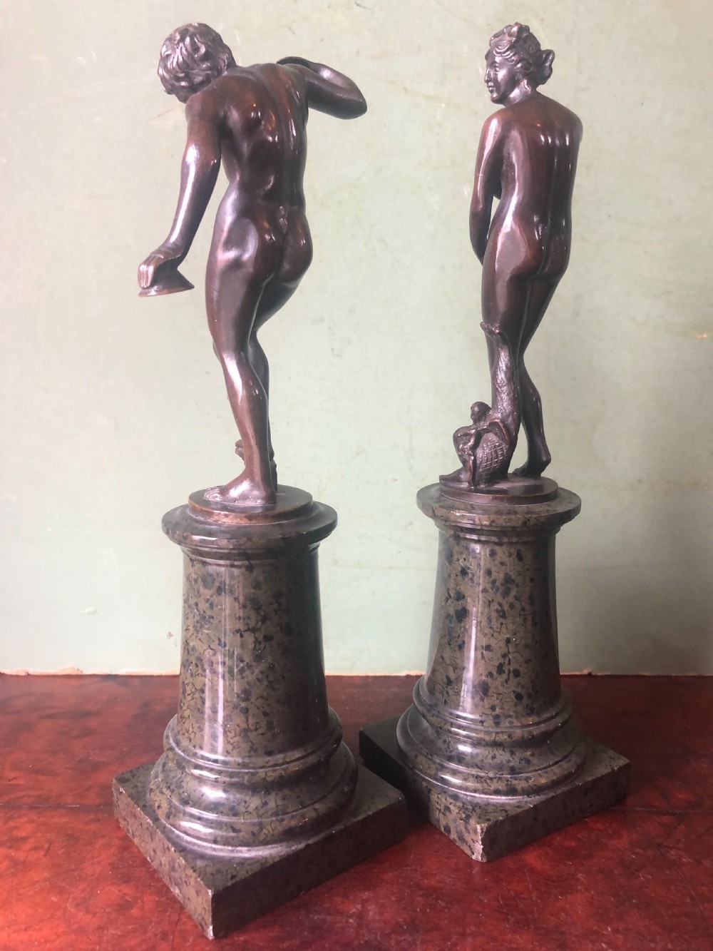 A pair of late nineteenth-century dark patinated bronze classical nude figures mounted on tall cylindrical dark marble column bases. View XI