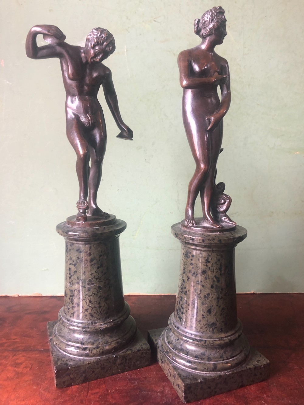 A pair of late nineteenth-century dark patinated bronze classical nude figures mounted on tall cylindrical dark marble column bases. View XIII