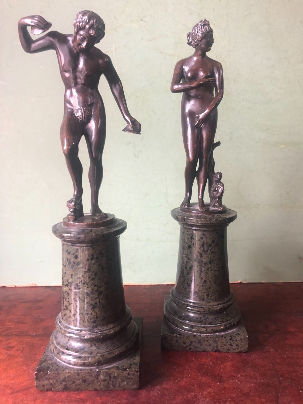 A pair of late nineteenth-century dark patinated bronze classical nude figures mounted on tall cylindrical dark marble column bases. View XIV