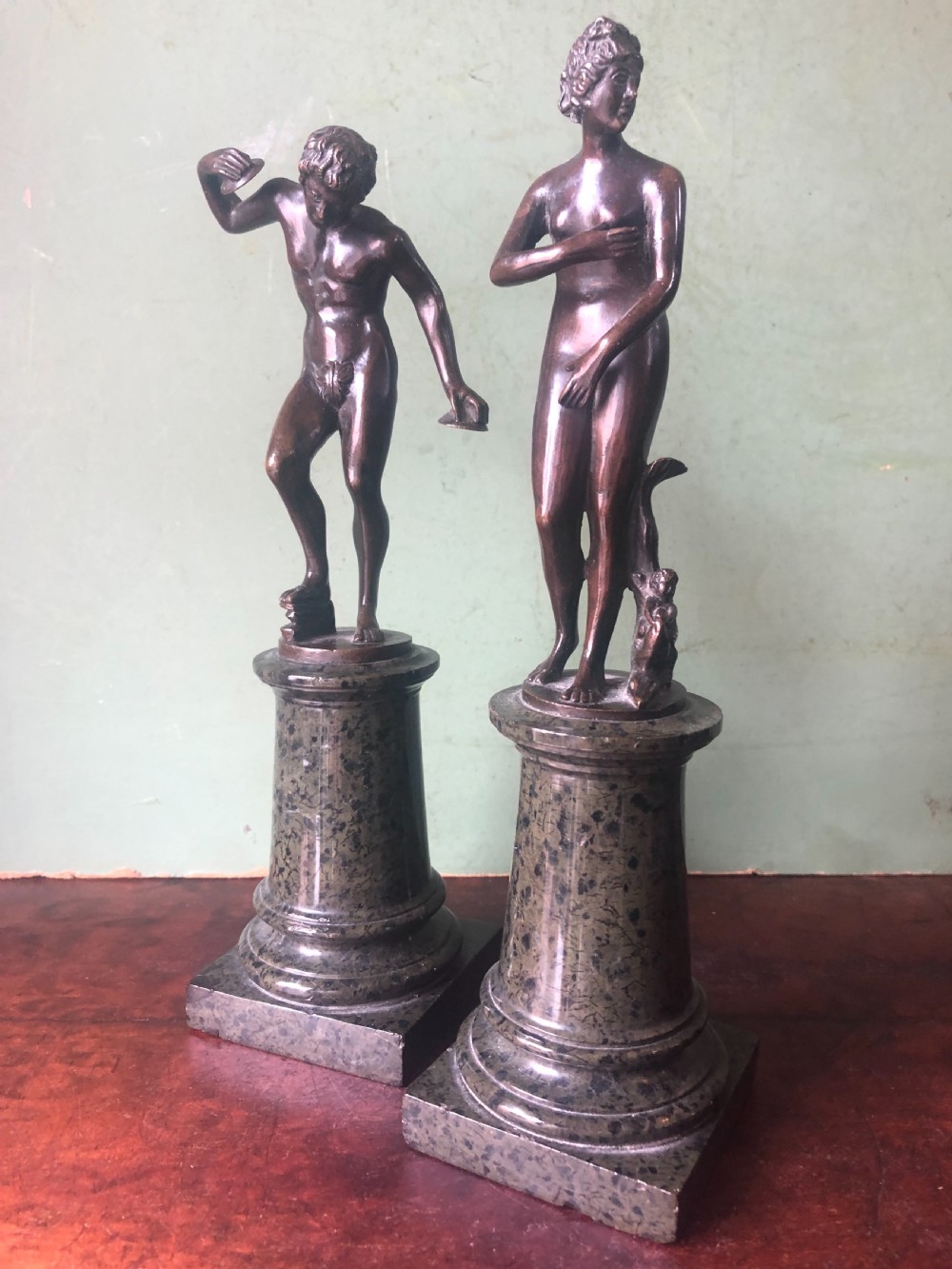 A pair of late nineteenth-century dark patinated bronze classical nude figures mounted on tall cylindrical dark marble column bases. View XV