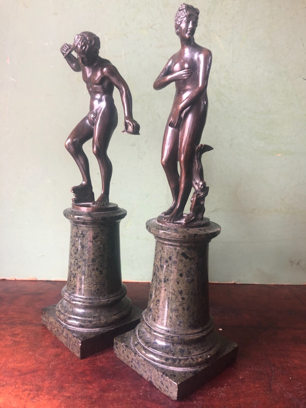 A pair of late nineteenth-century dark patinated bronze classical nude figures mounted on tall cylindrical dark marble column bases. View XVI