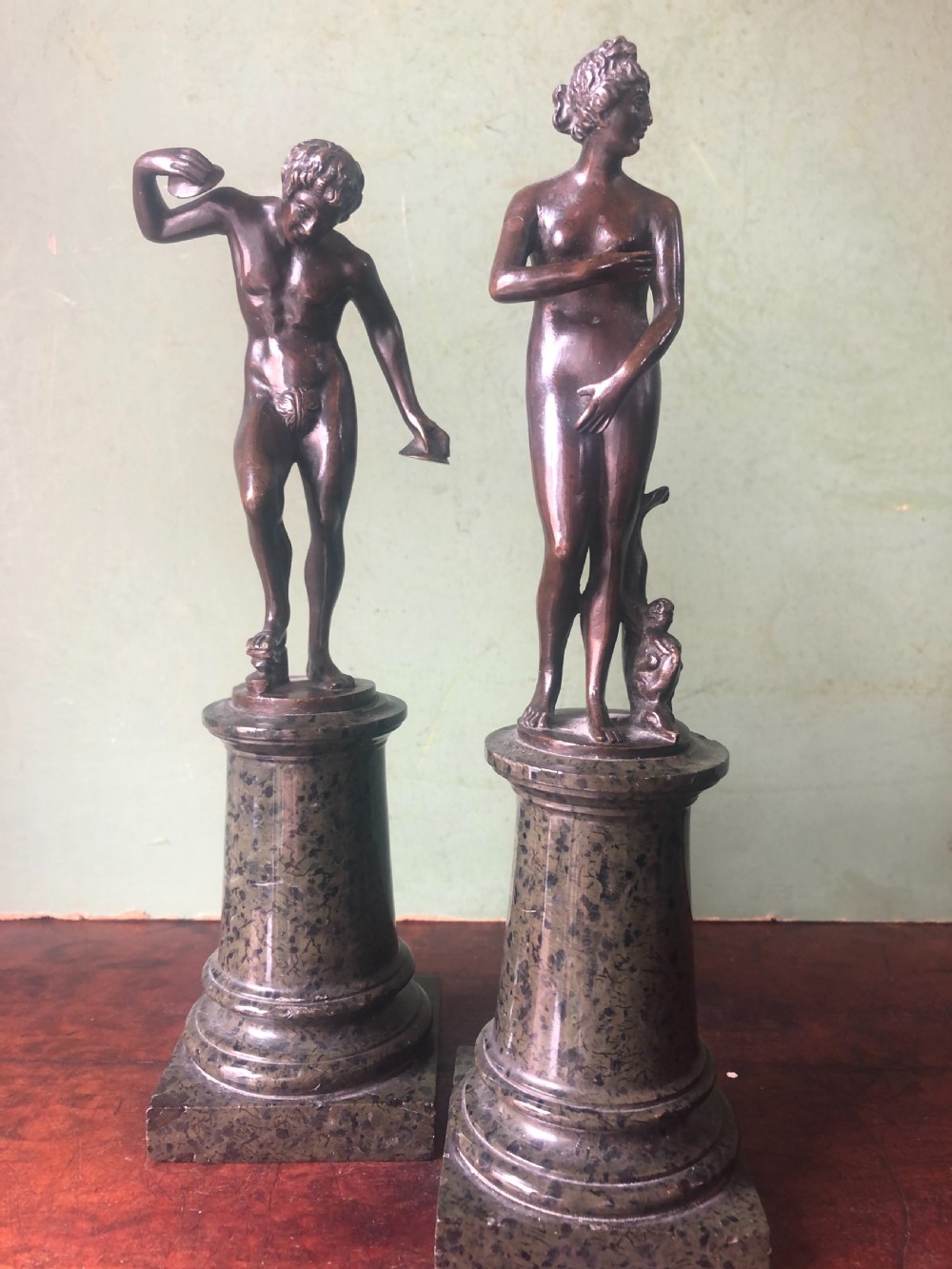 A pair of late nineteenth-century dark patinated bronze classical nude figures mounted on tall cylindrical dark marble column bases. View XVII