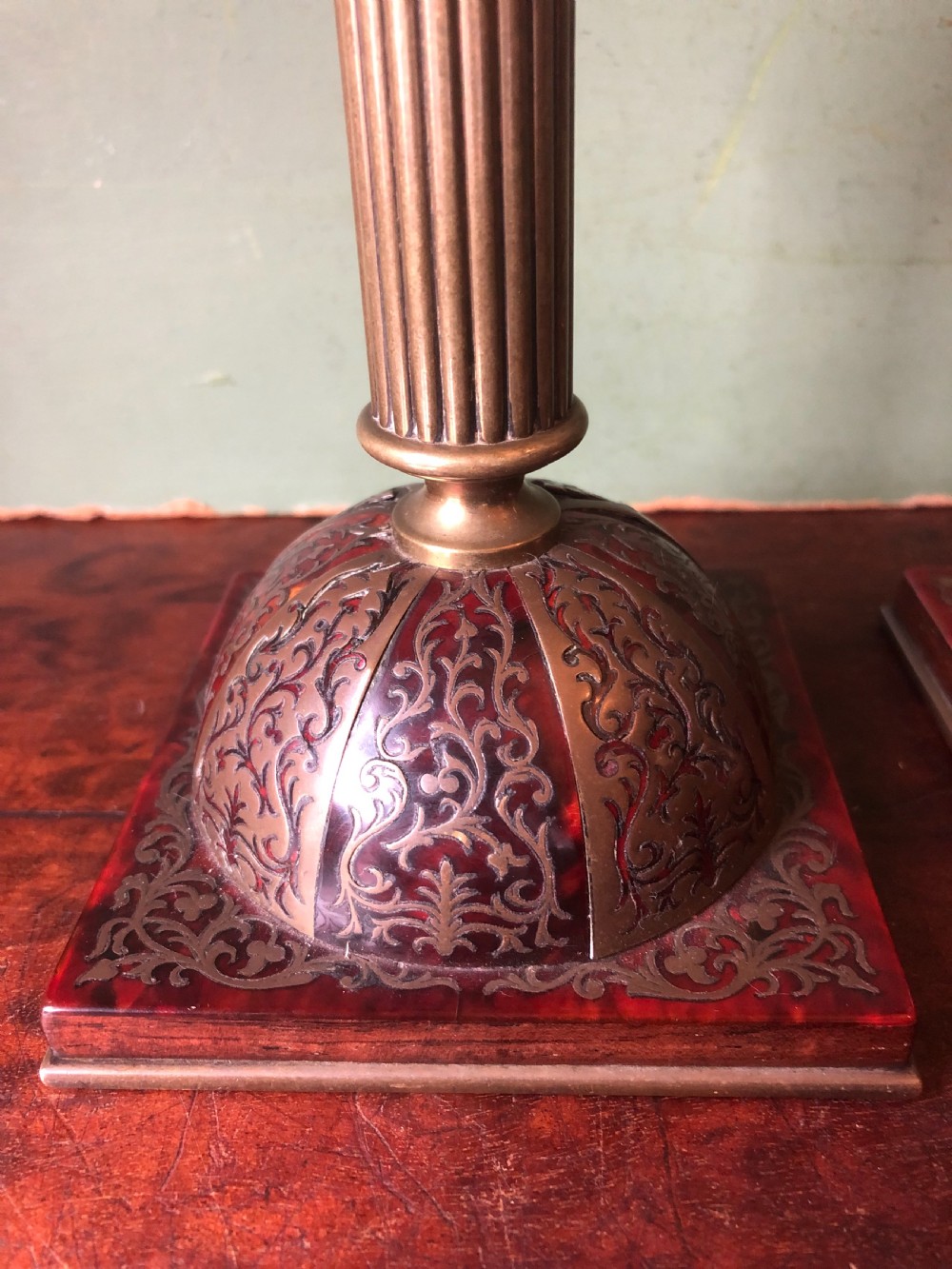 A pair of late 19th-century brass candlesticks featuring fluted columns supported by domed square bases inlaid with red tortoiseshell and engraved brass Boulle-work scroll motifs. View II