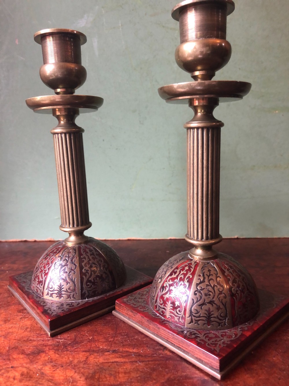 A pair of late 19th-century brass candlesticks featuring fluted columns supported by domed square bases inlaid with red tortoiseshell and engraved brass Boulle-work scroll motifs. View IX