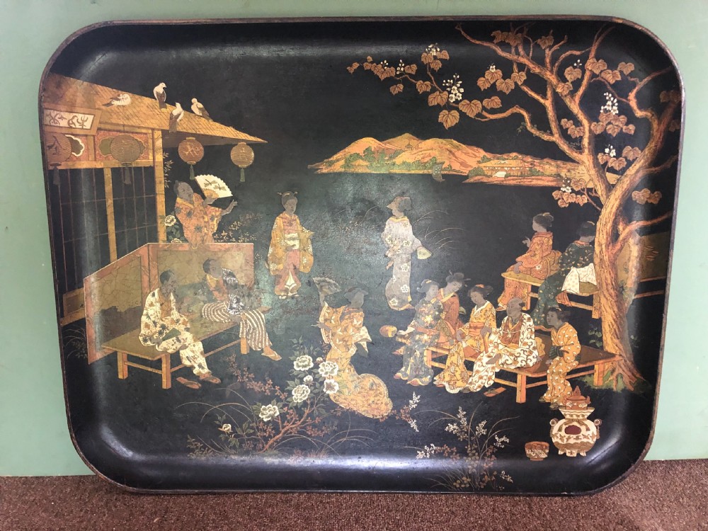 A mid-19th century rectangular black lacquer papier-mache tray decorated with hand-painted Japanese figures, traditional structures, and landscape scenery in gold and polychrome pigments. View II