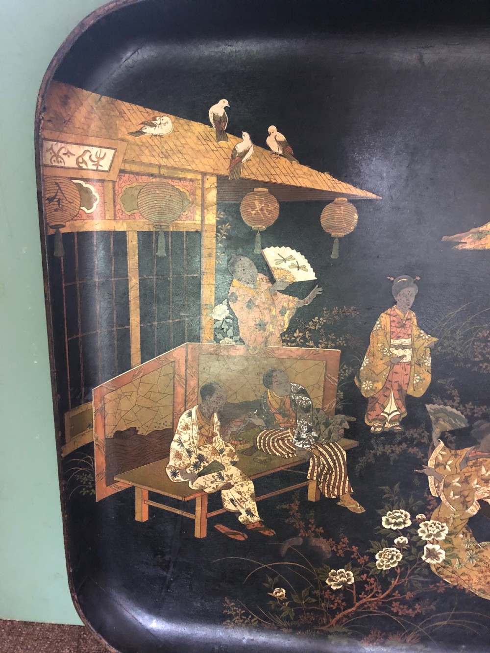 A mid-19th century rectangular black lacquer papier-mache tray decorated with hand-painted Japanese figures, traditional structures, and landscape scenery in gold and polychrome pigments. View IV