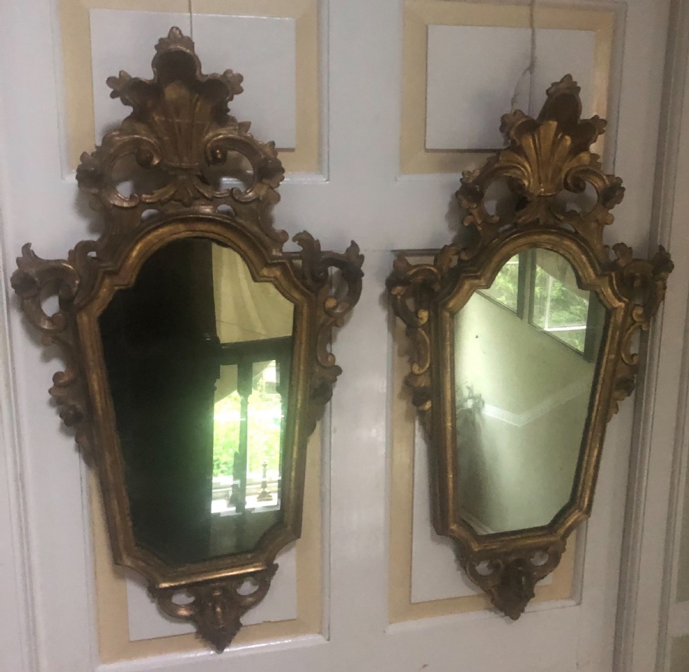 A pair of late eighteenth-century style carved giltwood pier mirrors featuring scrollwork cresting and shaped mirrored plates. View III