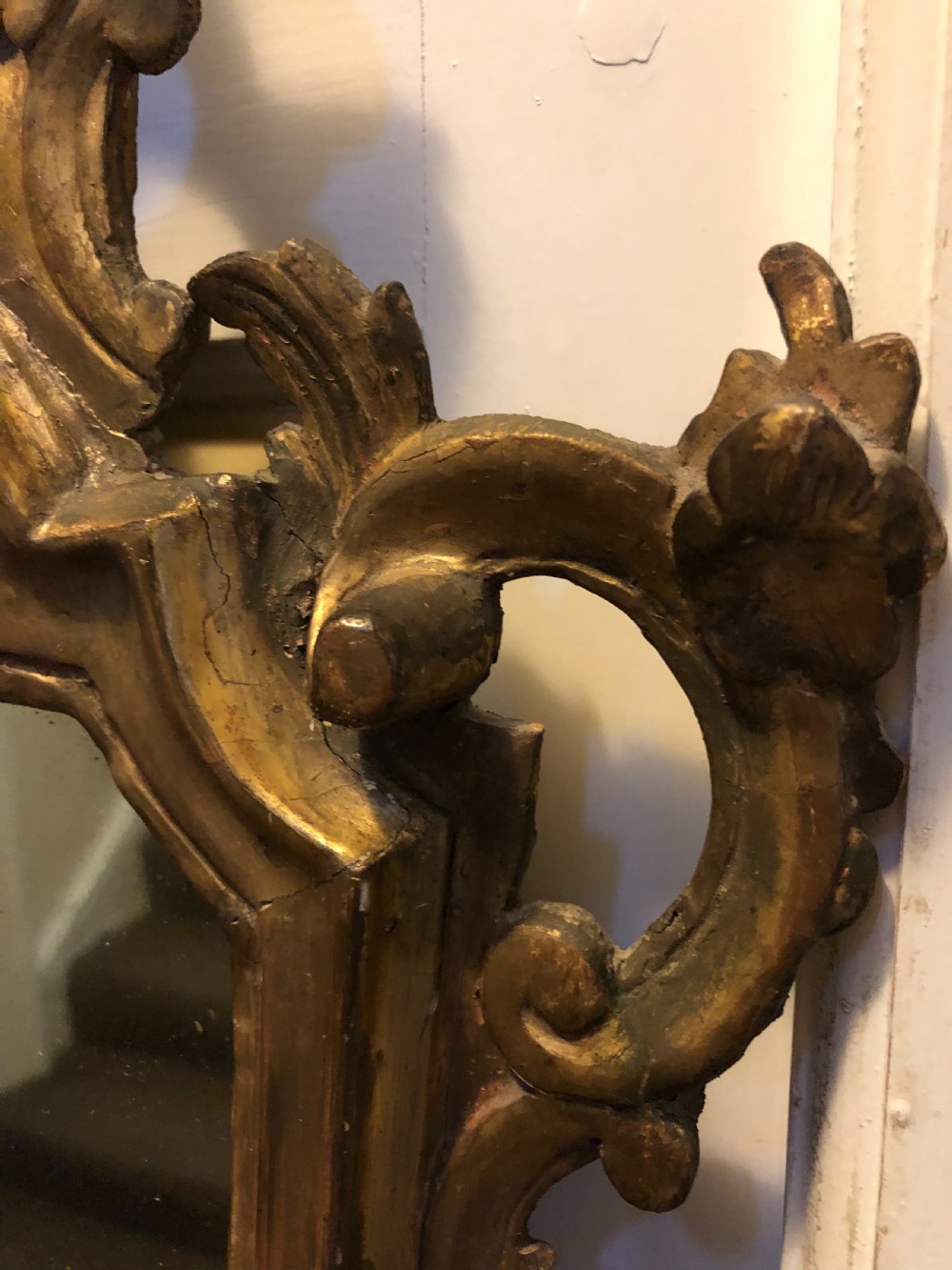 A pair of late eighteenth-century style carved giltwood pier mirrors featuring scrollwork cresting and shaped mirrored plates. View V