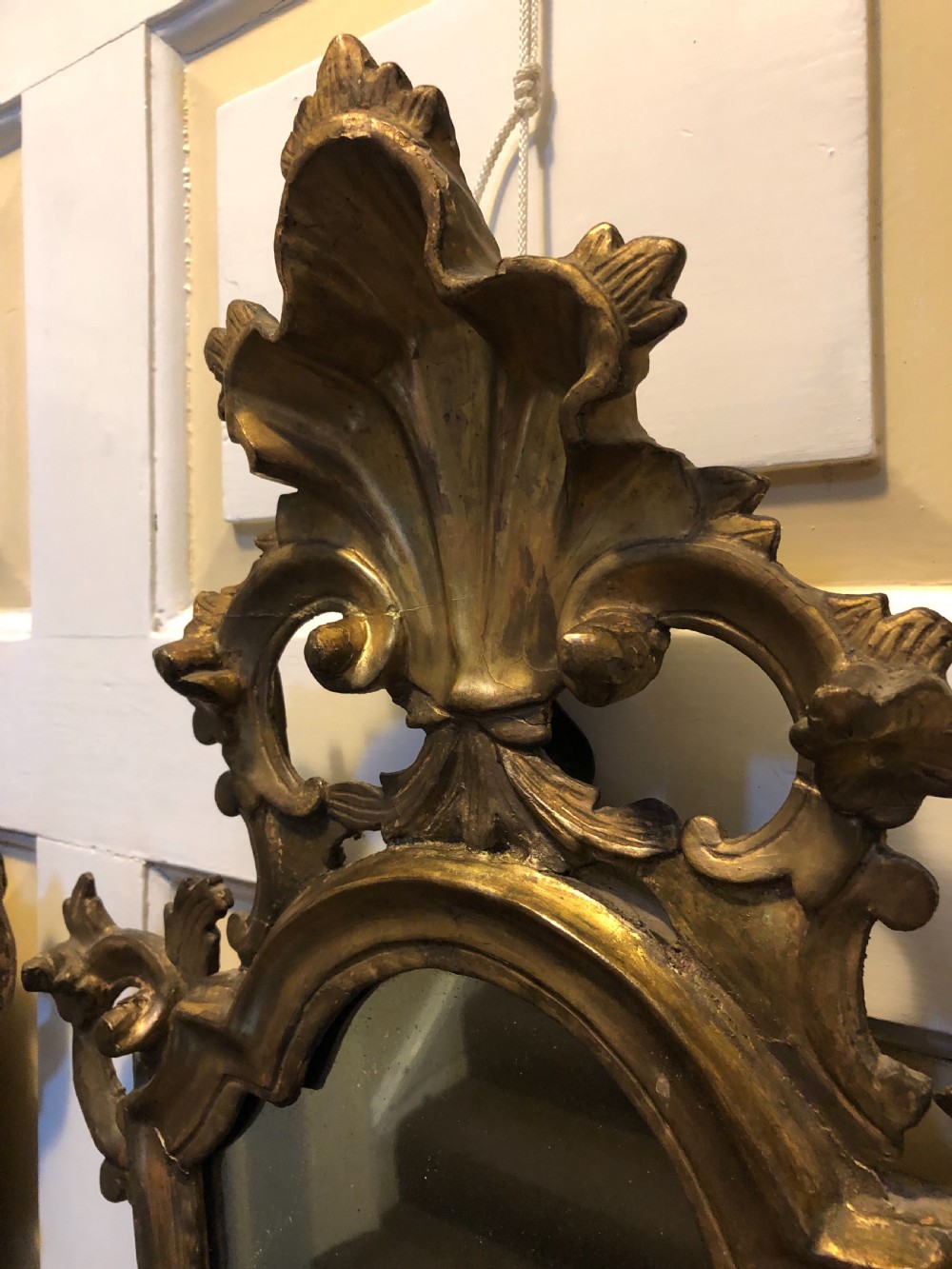 A pair of late eighteenth-century style carved giltwood pier mirrors featuring scrollwork cresting and shaped mirrored plates. View XII
