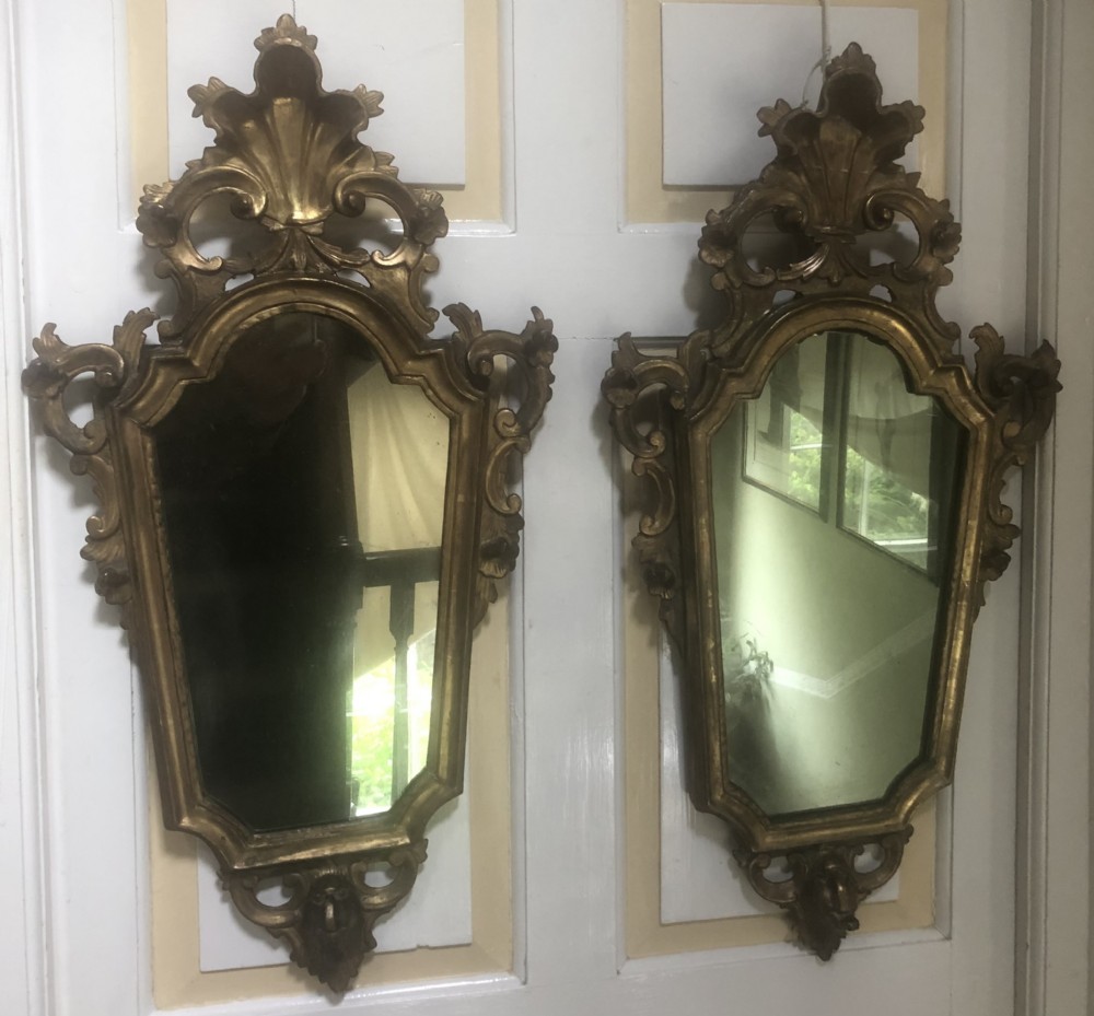 A pair of late eighteenth-century style carved giltwood pier mirrors featuring scrollwork cresting and shaped mirrored plates. View XX