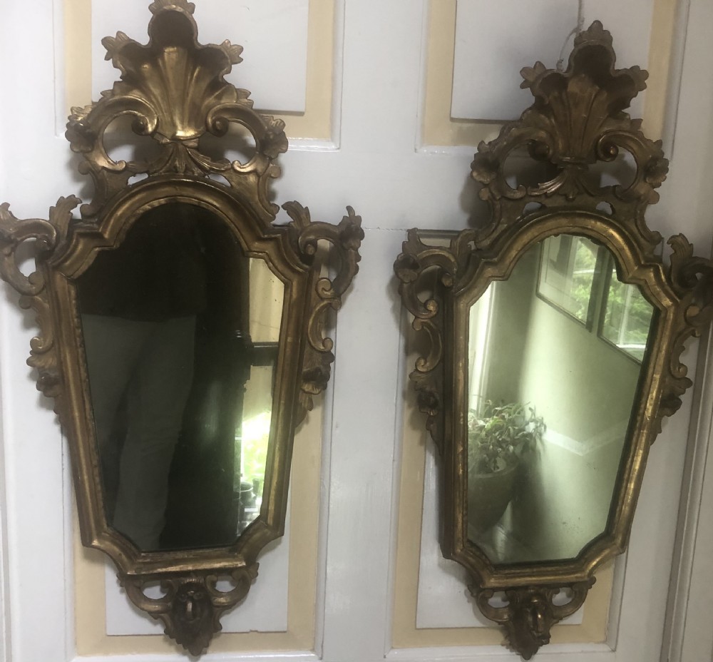 A pair of late eighteenth-century style carved giltwood pier mirrors featuring scrollwork cresting and shaped mirrored plates. View XXVIII