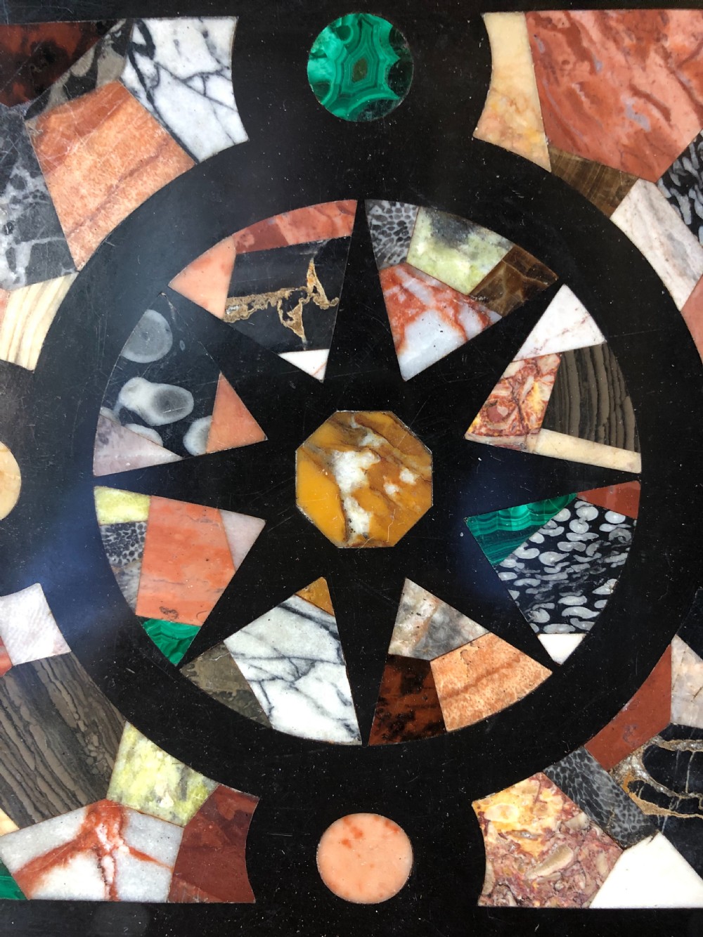 A square 19th-century Ashford black marble panel inlaid with colourful specimen marble geometric shapes forming a central star motif, set within a gilt wood frame with a top brass hanging ring. View III