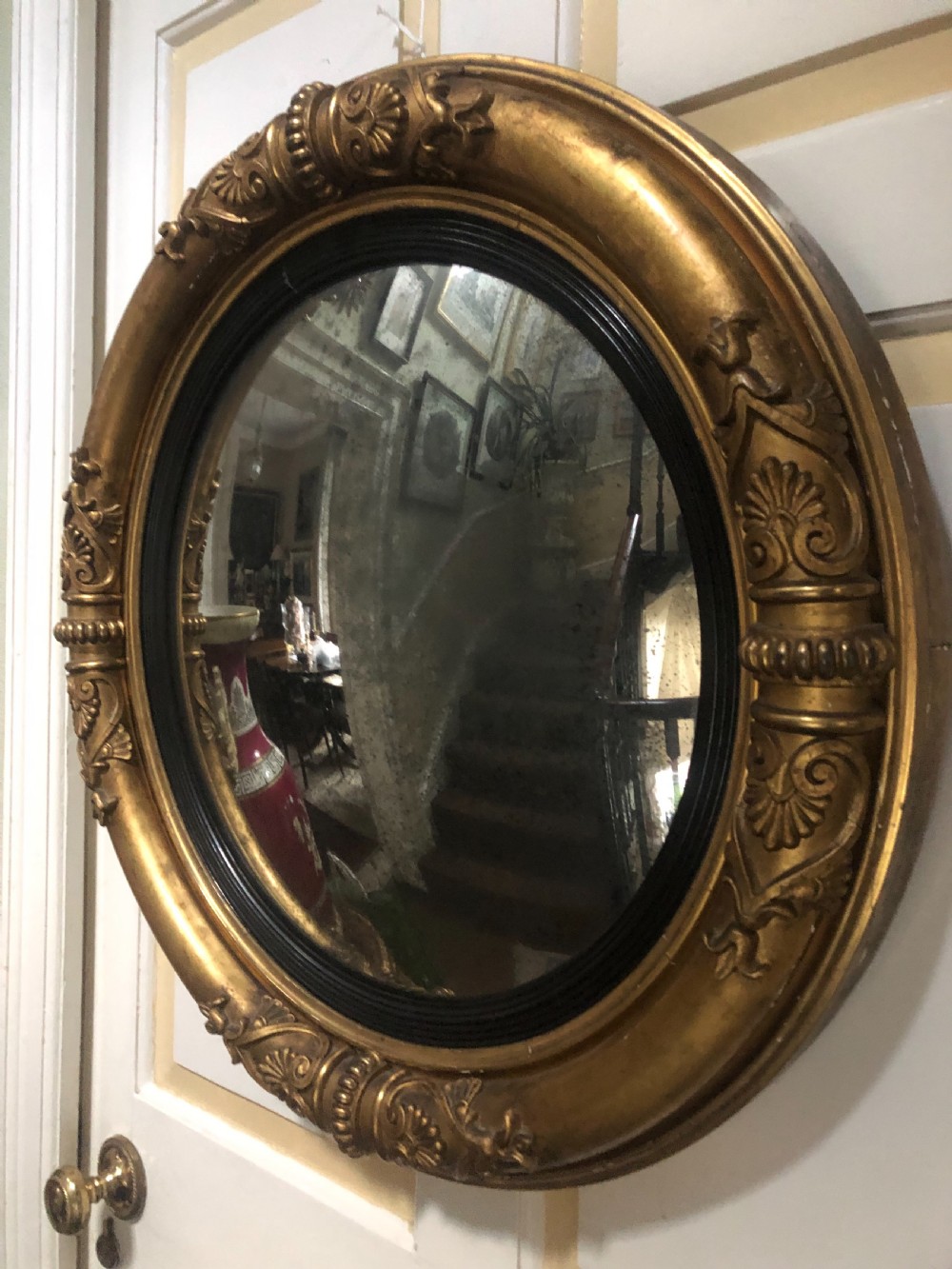 Early 19th-century circular Regency giltwood convex wall mirror decorated with anthemion leaf carvings and an ebonised reeded inner slip. View III