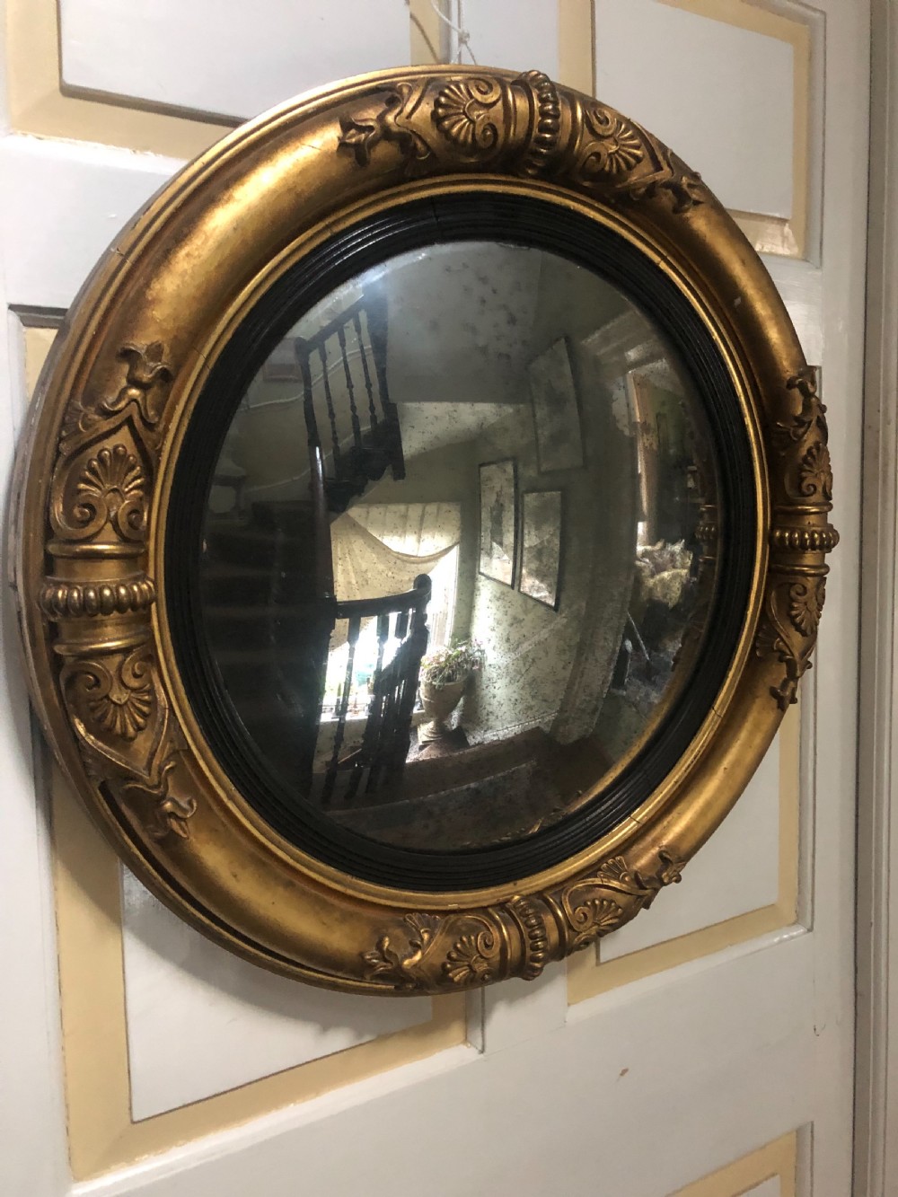 Early 19th-century circular Regency giltwood convex wall mirror decorated with anthemion leaf carvings and an ebonised reeded inner slip. View IV