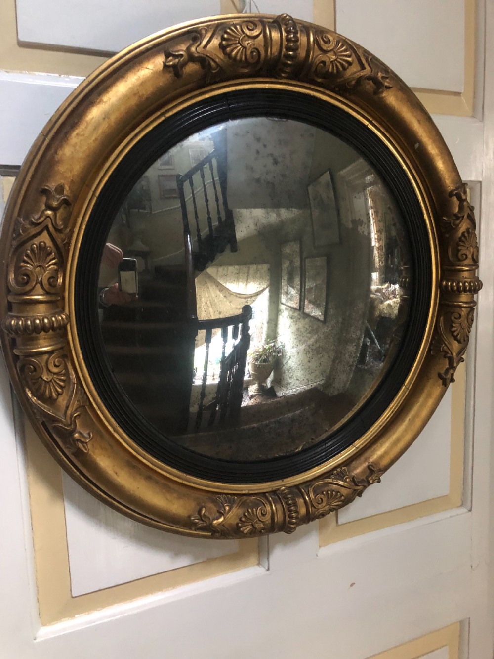 Early 19th-century circular Regency giltwood convex wall mirror decorated with anthemion leaf carvings and an ebonised reeded inner slip. View V