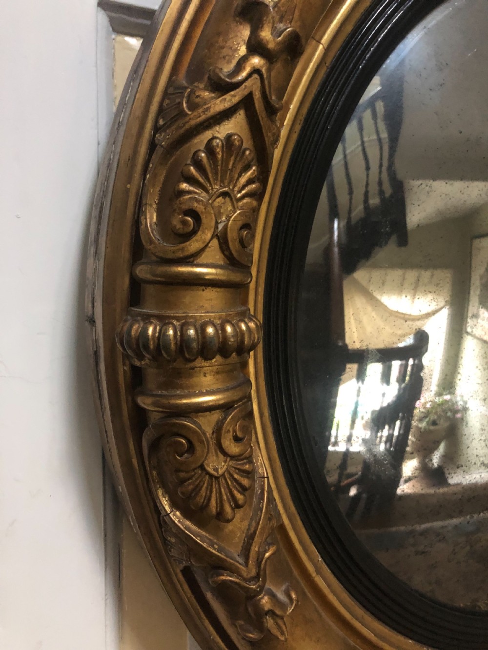 Early 19th-century circular Regency giltwood convex wall mirror decorated with anthemion leaf carvings and an ebonised reeded inner slip. View VI