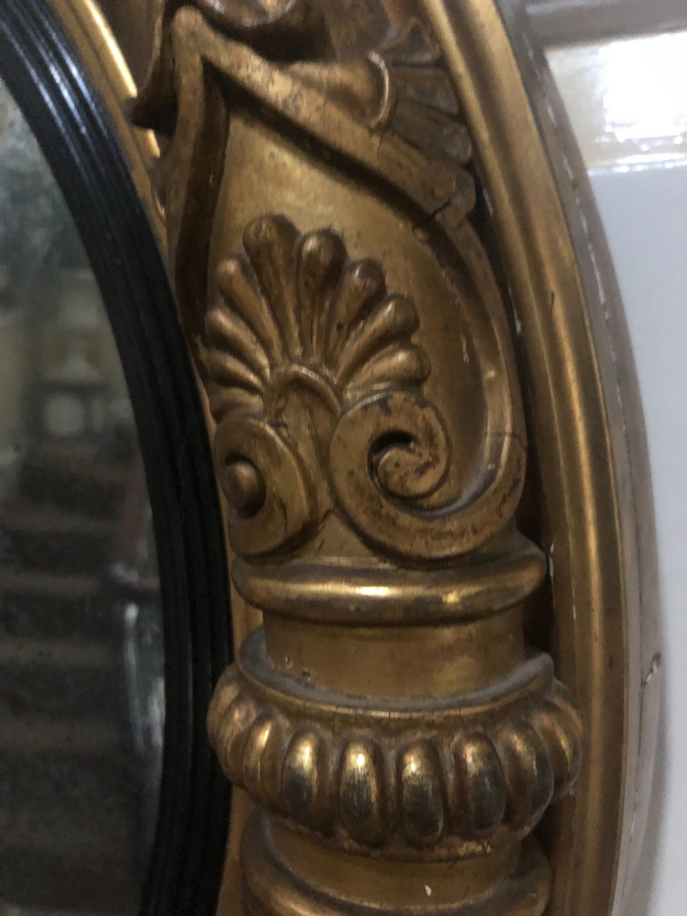 Early 19th-century circular Regency giltwood convex wall mirror decorated with anthemion leaf carvings and an ebonised reeded inner slip. View VII